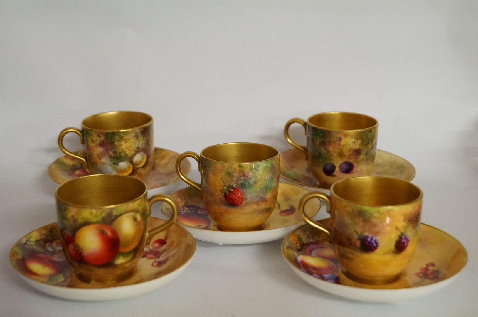 Five Royal Worcester coffee cups and saucers, each painted of various fruit, two painted by E.