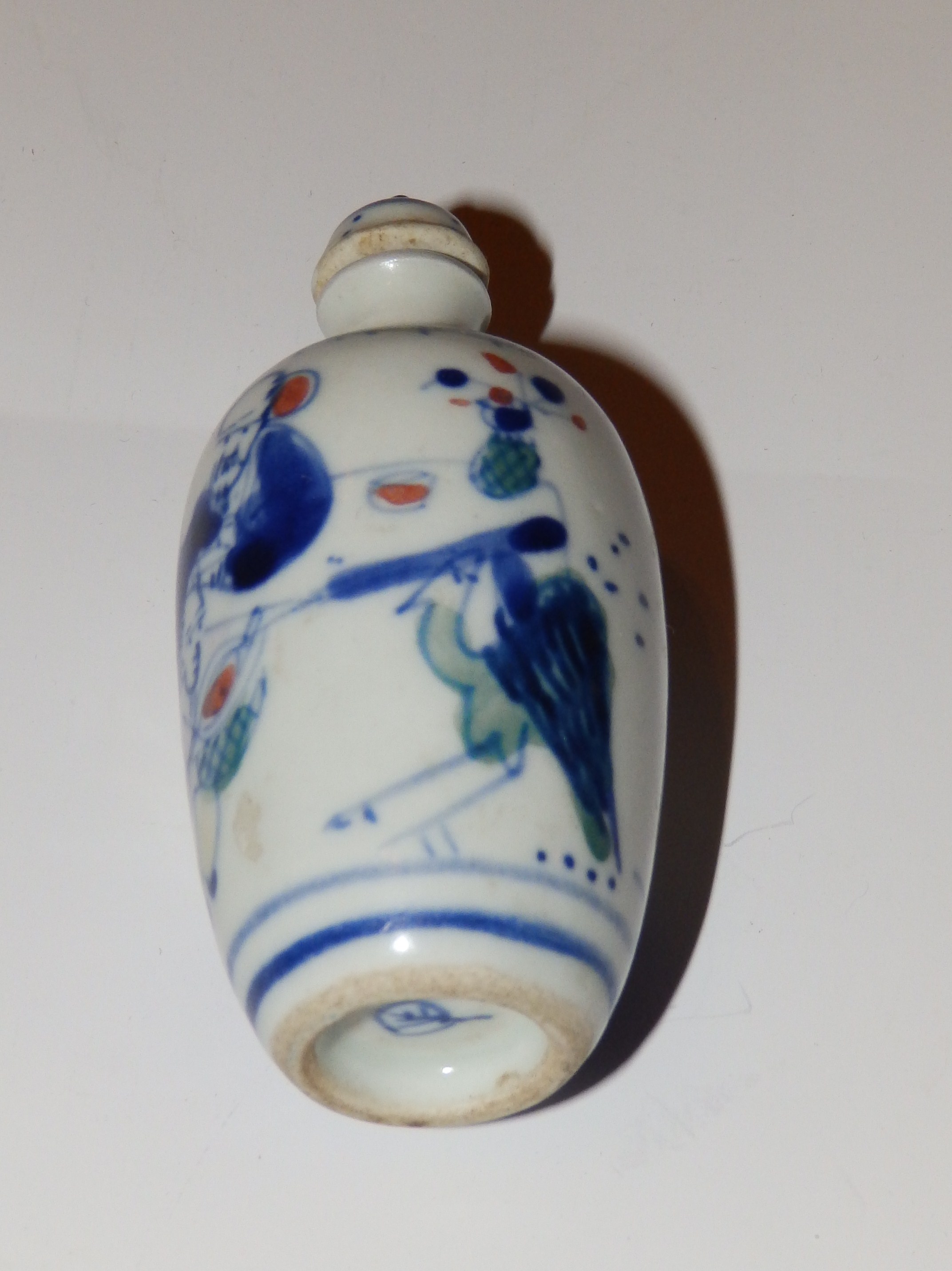 A Chinese porcelain snuff bottle, decorated in K`ang Hsi style underglaze blue with details in red