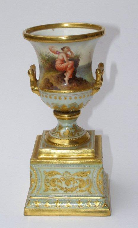 A small late 19thC Vienna porcelain two-handled campana shaped vase on pedestal, the front painted