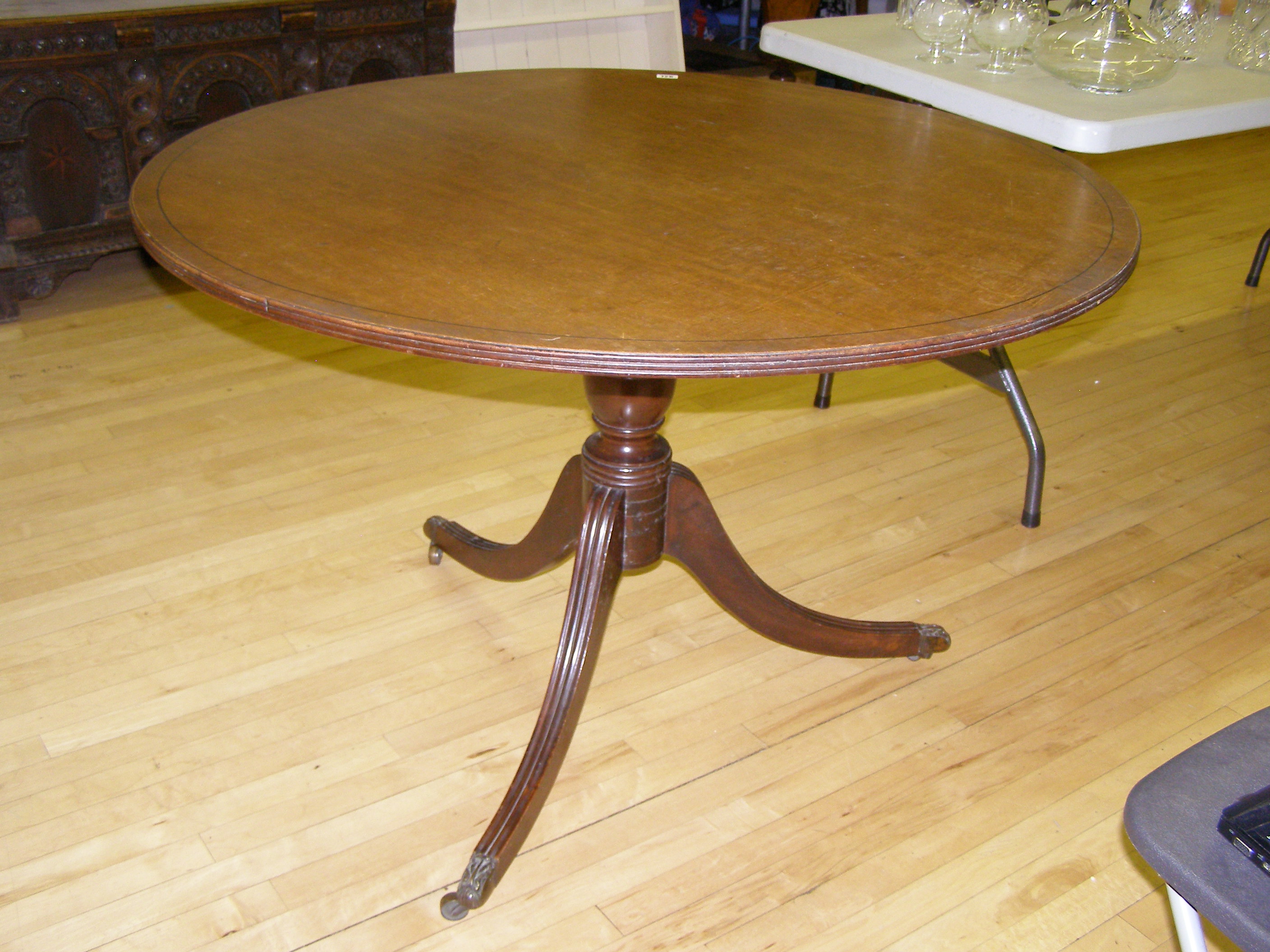 A circular mahogany tripod dining table