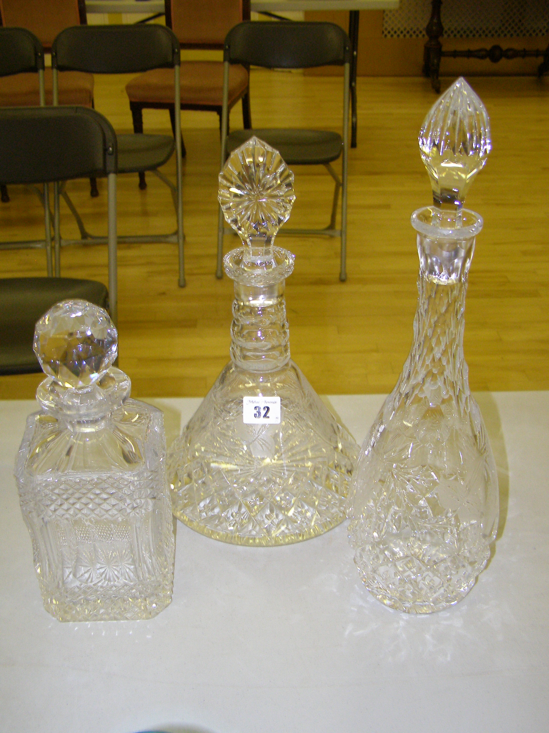 A modern cut glass ship`s decanter with engraved decoration together with two matching decanters (