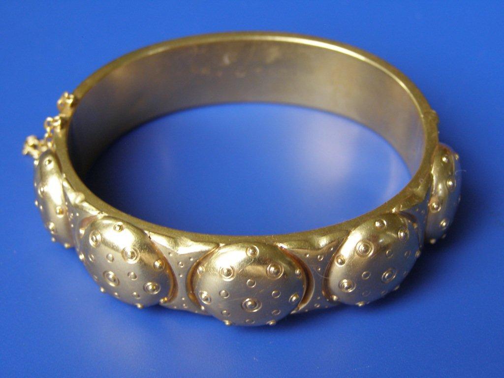 A yellow metal bangle, designed with four beaded domes to upper surface