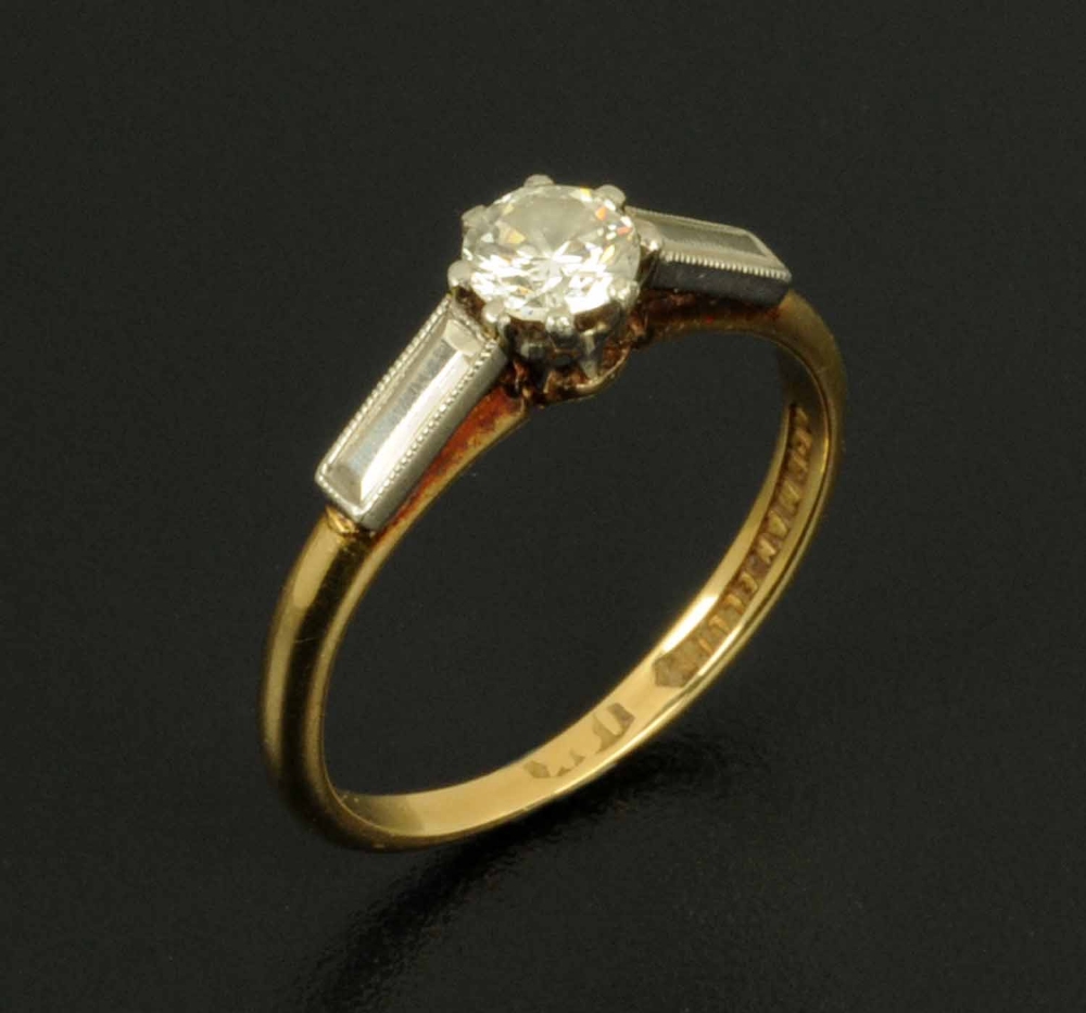 A solitaire diamond ring, with faceted white coloured metal shoulder, shank stamped "18 K", ring
