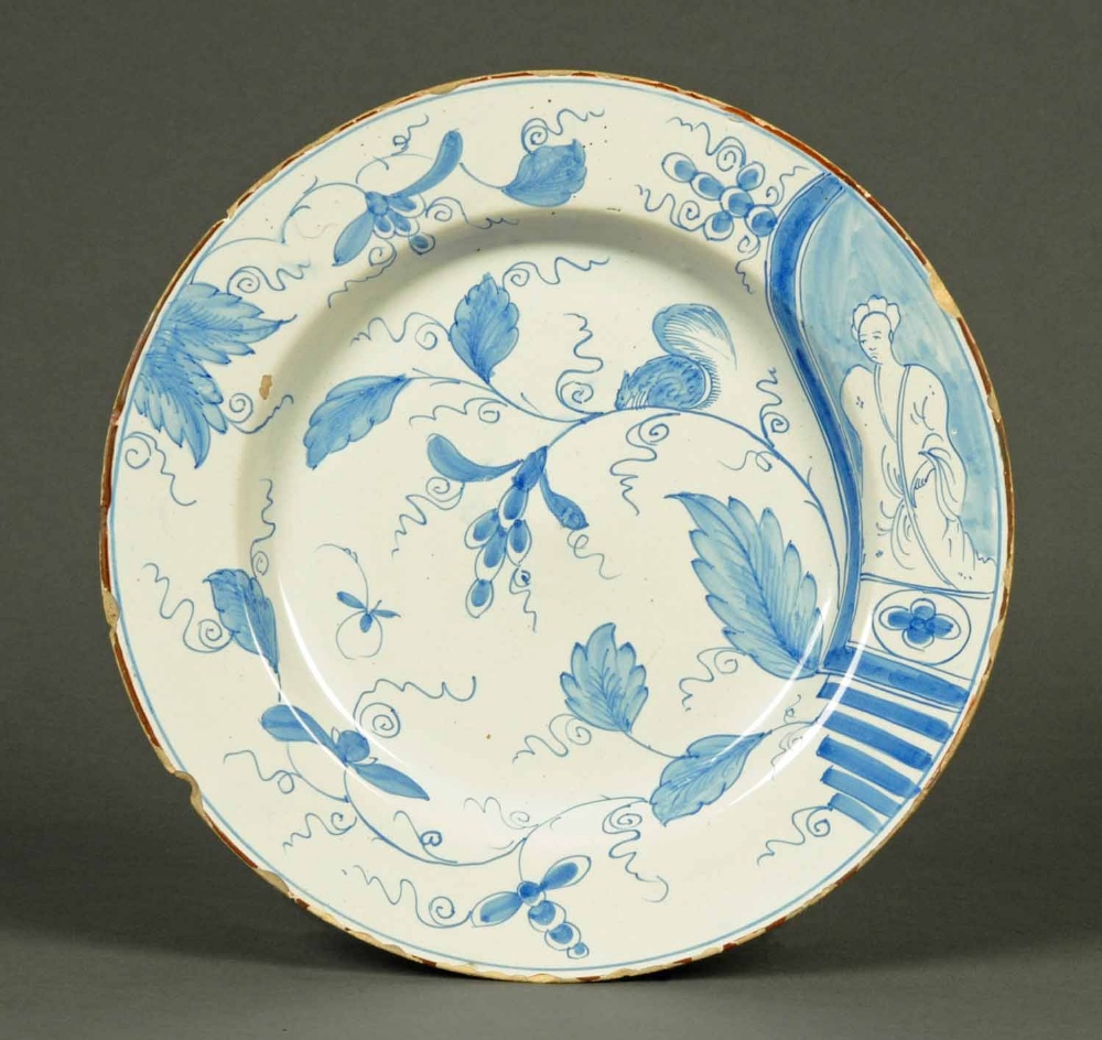 An English Delft charger, circa 1770, with figure to one side, squirrel and foliage, blue to duck