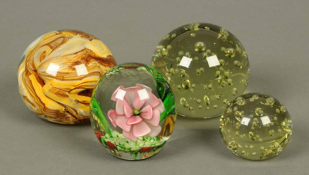 A large green glass paperweight with bubbles, one similar but smaller, one lily and frog pattern and