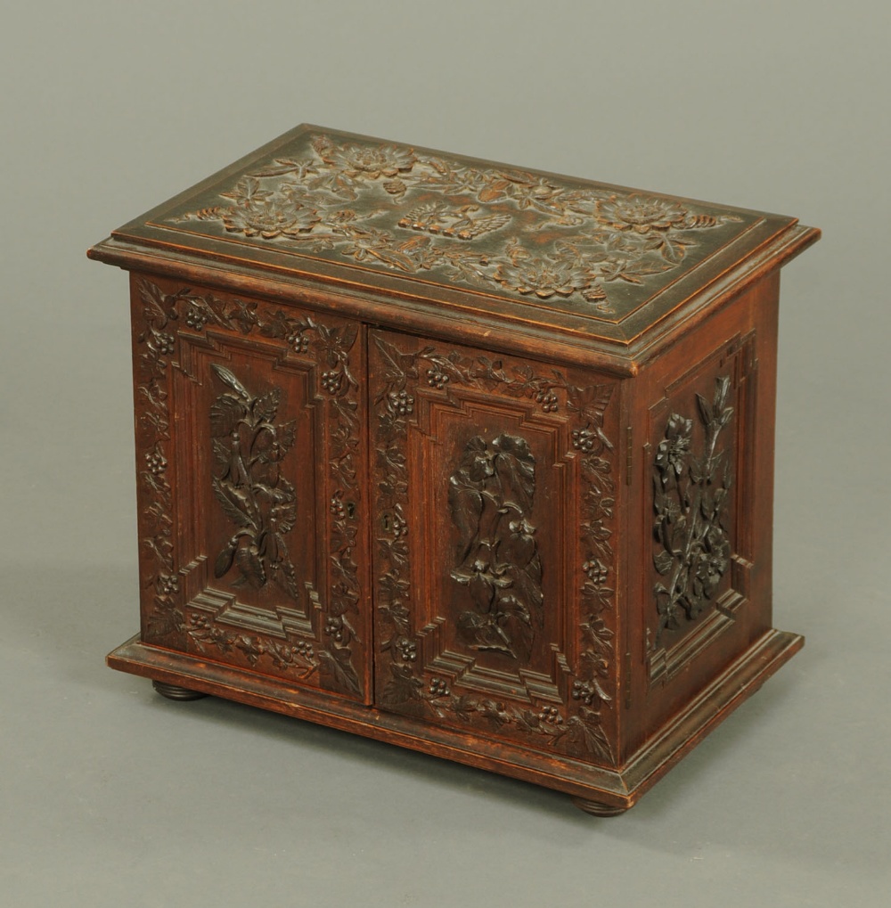 A Continental table top cabinet, decorated to the top with a carved spur and wings and foliate