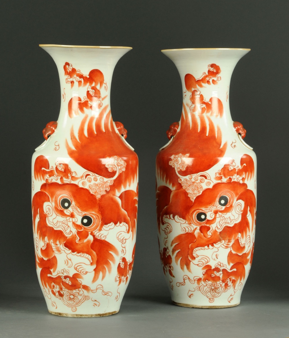 A pair of Chinese vases, each decorated with a dragon in orange glaze and with multiple character