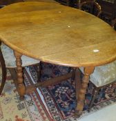 An early 20th Century oak oval gate-leg drop-leaf dining table on bobbin turned supports in the 17th