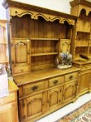 An elm dresser in the 18th Century manner, the plate rack with two panelled doors over two drawers