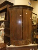 A 19th Century bow fronted corner cupboard with two doors opening to reveal various shelving over