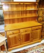 A light pine Ercol kitchen dresser, the three open shelves above three drawers over three cupboard