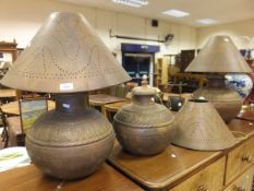 A set of three Middle Eastern embossed copper table lamps and pierced shades, together with