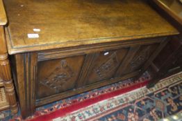 An oak coffer in the 18th Century taste, the plank top over three panelled front with carved diamond