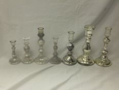 A collection of seven silver wash moulded glass candlesticks