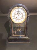 A late Victorian black slate cased mantel clock, the eight day movement with visible escapement