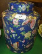 A Chinese porcelain cylindrical jar and cover decorated with butterflies and flowers on a blue