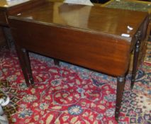 A 19th Century mahogany Pembroke table raised on turned and ringed legs to brass caps and
