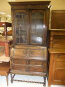 An oak bureau bookcase with leaded glazed doors above a fall front over three various drawers on