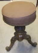 A Victorian walnut revolving piano stool, the circular upholstered top above an acanthus carved