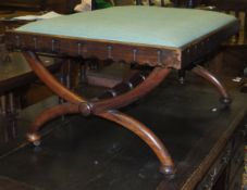 A 19th Century walnut rectangular stool raised on X-framed supports and wooden castors, united by