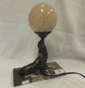 An Art Nouveau style lamp, the body in the form of a seal balancing the pink glass spherical shade