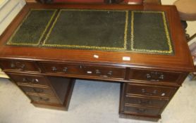 A reproduction mahogany desk, the green inset top above three frieze drawers over two banks of three