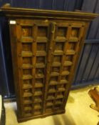 An Indian hardwood cabinet, the two panelled doors enclosing shelving raised on a bracket foot base