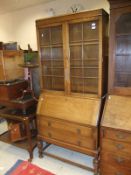 An early 20th Century oak bureau bookcase, the two glazed doors opening to reveal various shelving