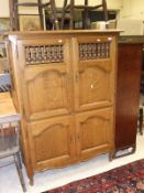 An oak cupboard with two pairs of panelled doors, the top with turned bobbin decoration, on shaped