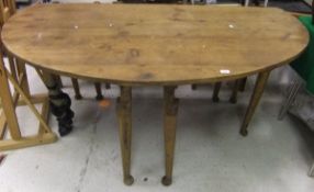 A large oval pitch pine kitchen table on turned legs to pad feet