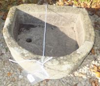 A D-shaped natural stone trough with circular drain hole