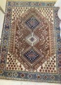 A Persian rug, the three central linked diamond shaped medallions in blue, cream and terracotta,