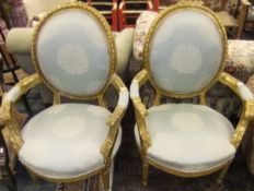 A pair of carved and gilded framed elbow chairs in the French taste, upholstered in a light blue