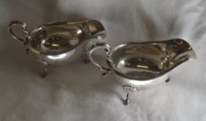 A pair of George V silver sauce boats with scrolling handle, raised on three hoof feet (Sheffield