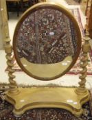 A pine toilet mirror, the oval plate on two barley-twist supports on a shaped base