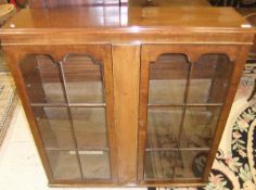 An early 20th Century mahogany display cabinet, the two glazed doors opening to reveal various