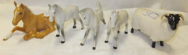 A Beswick pottery Palomino foal (seated), three small Beswick pottery piebald horses and a Beswick