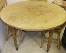 A circular pine dining table on ringed and turned supports