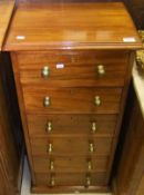 A slender mahogany chest of six drawers with brass handles in the early 19th Century manner