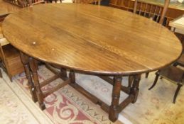 A Lion House oval oak large drop-leaf dining table in the 18th Century manner, on turned and