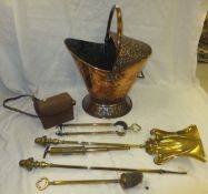 A copper coal helmet with all-over flower decoration, a set of brass fire tools, and a camera