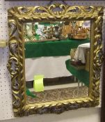 A giltwood and gesso wall mirror, the frame with scrolling decoration