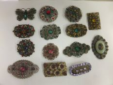 A box containing various mid 20th Century filigree and paste set stone brooches