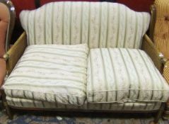A mahogany framed double caned Bergere two seater sofa, the arms terminating in carved ram's