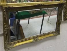 A modern gilt framed rectangular wall mirror with foliate carved decoration and bevelled edge plate