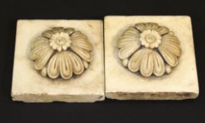 A pair of 19th Century carved marble roundels of flower head design, on square marble slab bases, 13