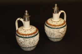 A pair of glazed stoneware jugs, the necks with white metal mounts and stoppers, the main bodies