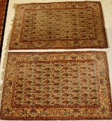 A pair of Kashan rugs, the central panel set with repeating hook motifs on a cream ground with