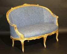 A French carved giltwood framed canape in the Louis XV taste raised on cabriole supports to scroll