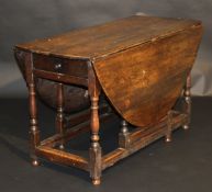 An 18th Century oak oval gate leg drop leaf dining table, the plain top above a single end drawer